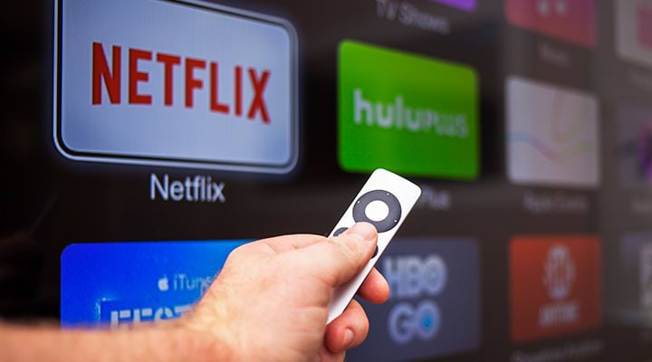 Person holding a Fire Stick remote in front of a smart TV, representing streaming capabilities